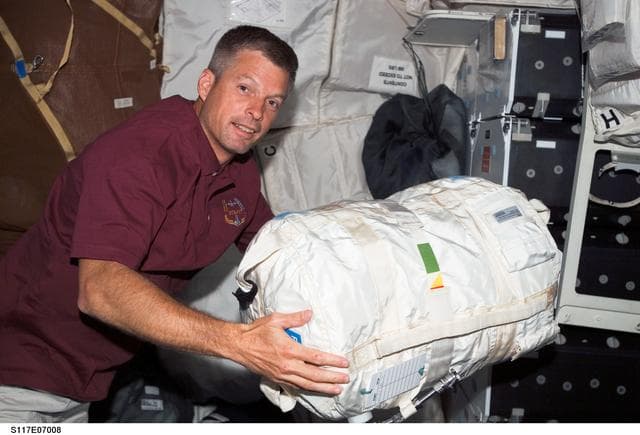 NASA image: Swanson, STS-117 MS moves stowage bag on the MDDK of Space Shuttle Atlantis