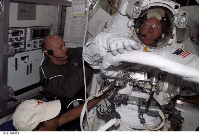 NASA image: Kelly and Wilson attach the SAFER to Fossums EMU during STS-121 / Expedition 13 joint operations