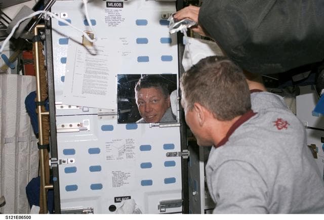 NASA image: Fossum wets his hair for washing during  STS-121 / Expedition 13 joint operations
