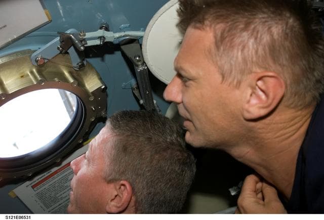 NASA image: Fossum and Sellers look out a window in the Pirs DC during STS-121 / Expedition 13 joint operations