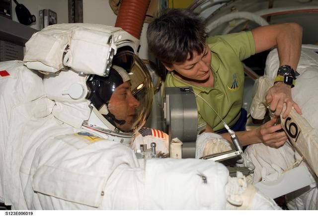 NASA image: Whitson assisting Linnehan with his EMU in the A/L during Joint Operations