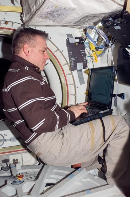NASA image: Johnson uses laptop computer near the A/L hatch in the MDDK during Joint Operations