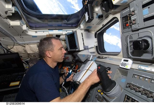NASA image: STS-125 MS5 Andrew Feustel works on the Flight Deck during Flight Day 7