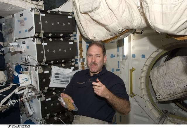 NASA image: STS-125 MS3 John Grunsfeld enjoys a meal in the Middeck