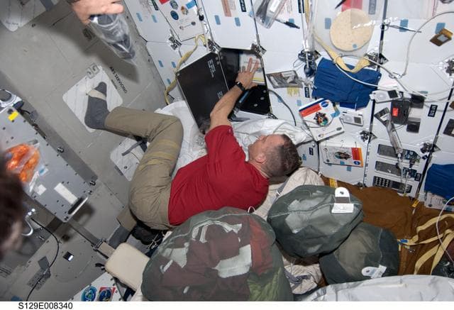 NASA image: CDR Hobaugh works to stow equipment on the Atlantis Middeck