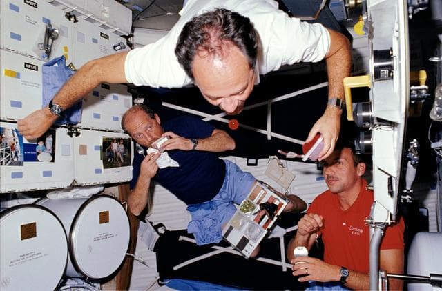 NASA image: STS-26 crewmembers experiment with microgravity and eat on middeck
