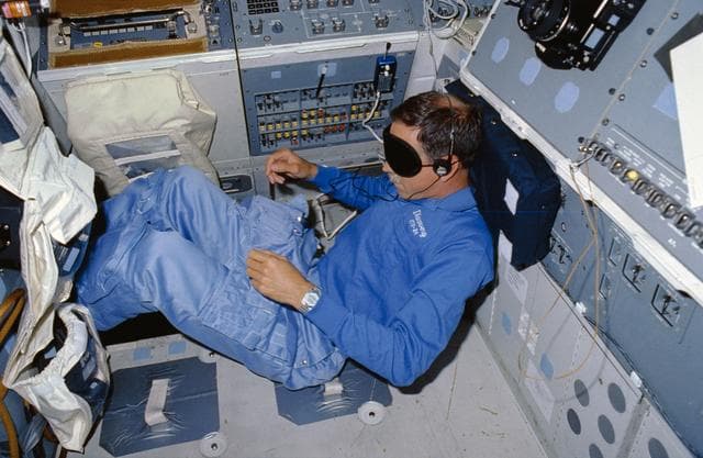 NASA image: STS-26 Pilot Covey, wearing sleep mask, rests on aft flight deck