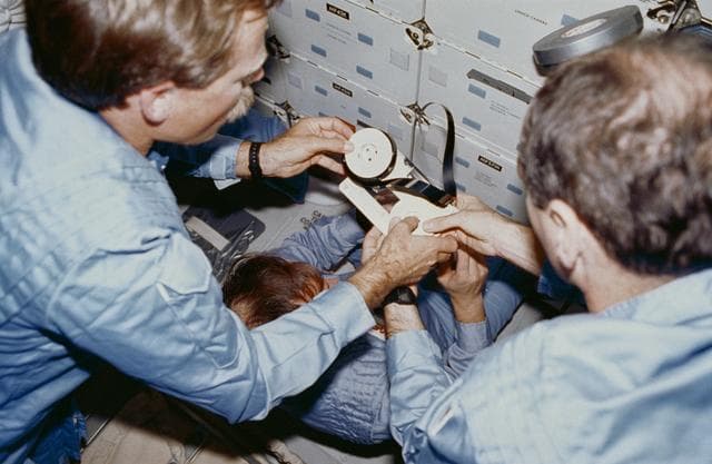 NASA image: STS-27 Atlantis, OV-104, crewmembers repair 3/4 inch video reel on middeck