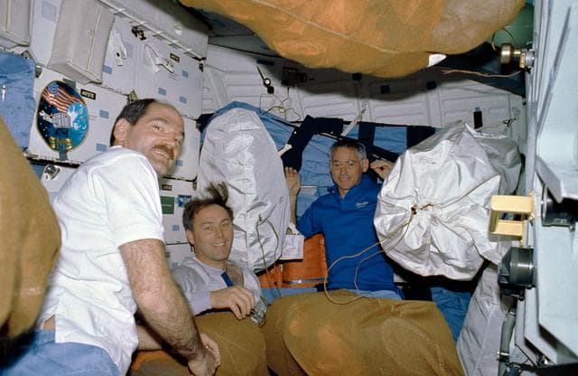 NASA image: STS-27 crewmembers surrounded by net stowage bags on middeck