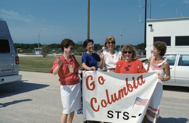 NASA image: STS-28 crewmembers' wives at KSC shuttle landing facility (SLF) with banner