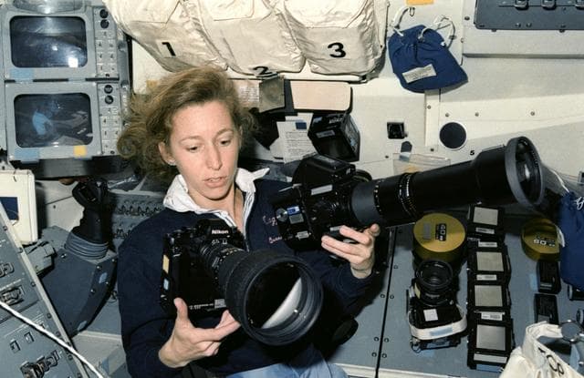 NASA image: STS-32 Mission Specialist Ivins juggles camera equipment on aft flight deck
