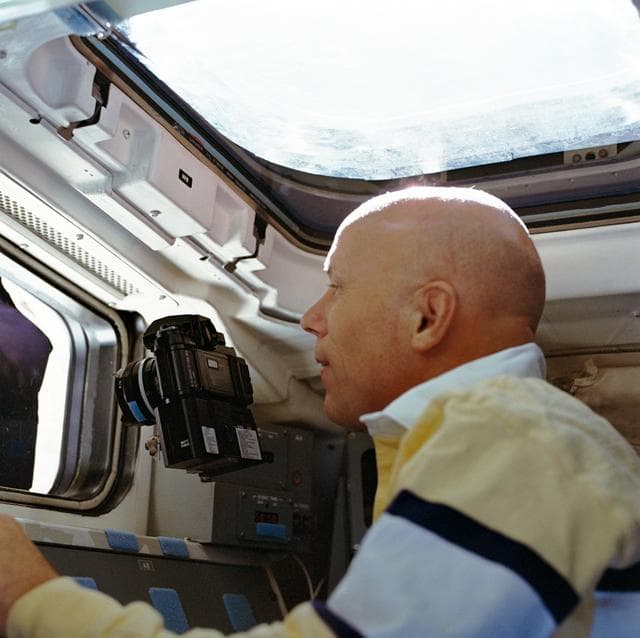 NASA image: STS-33 Mission Specialist Musgrave points camera out aft flight deck window