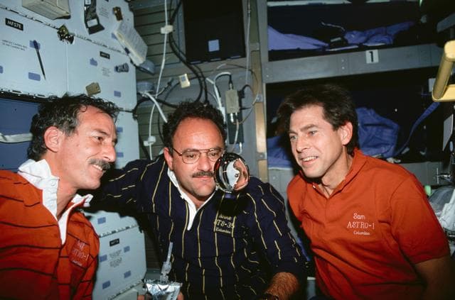 NASA image: STS-35 crewmembers watch a sphere of water float on OV-102's middeck