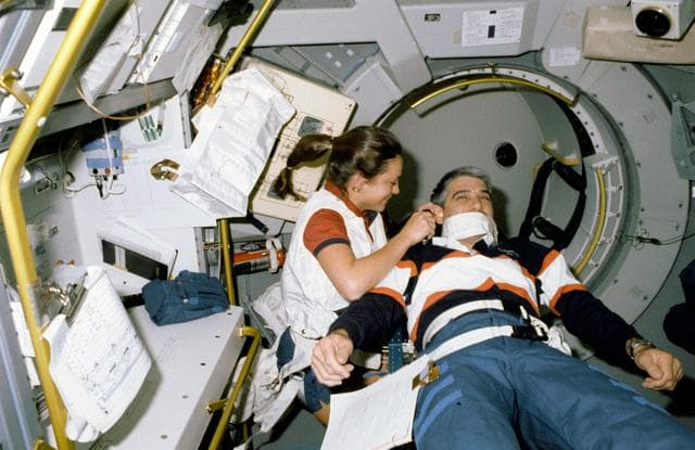 NASA image: STS-40 MS Jernigan, working at SLS-1 Rack 1, examines Pilot Gutierrez's ear