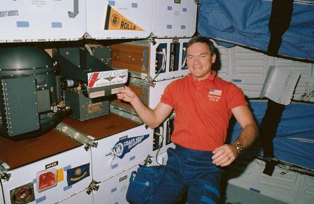 NASA image: STS-41 MS Melnick displays US Coast Guard decal on OV-103's middeck