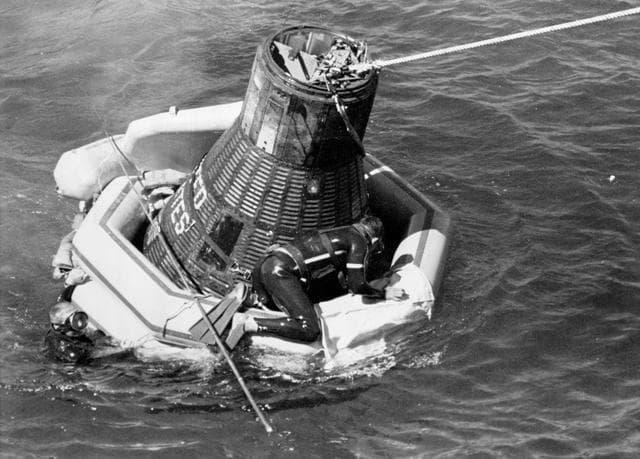 NASA image: Navy frogman astride Sigma 7 floatation collar to secure tow line