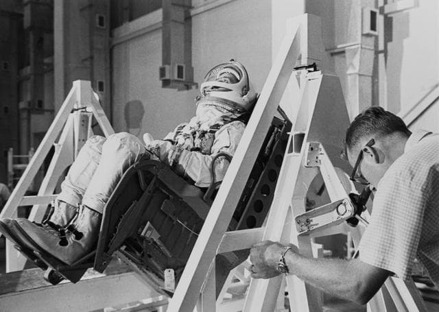 Astronaut Edward White being weighed and balanced in spacecraft seat