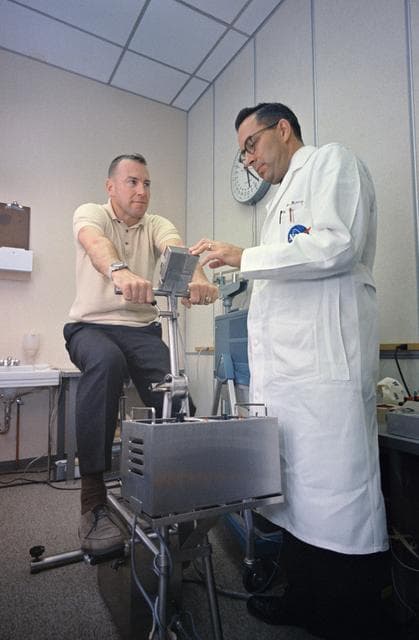 NASA image: Berry examines Lovell following a workout on exercise machine
