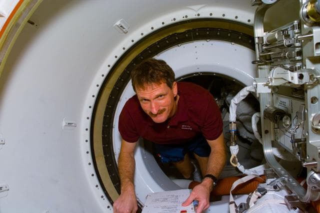 NASA image: Mission Specialist Joe Tanner floats through the tunnel adapter