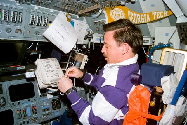 NASA image: Pilot Scott Horowitz fashions cord loop fasteners for a contingency spacewalk