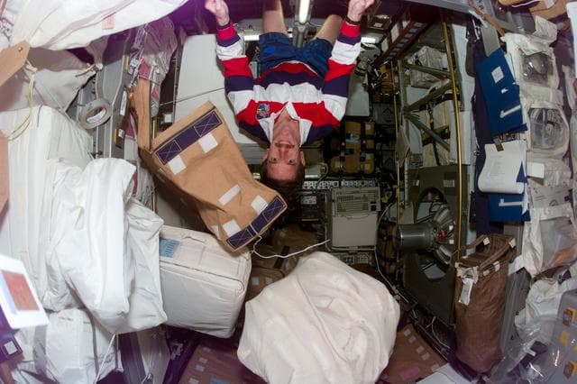 NASA image: MS Reilly clings to the ceiling of the Spacehab