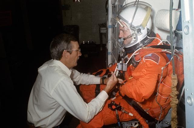 NASA image: STS-41 MS Akers assisted by technician on SMS middeck at JSC