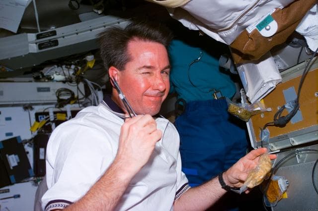 NASA image: Robinson on middeck preparing a meal