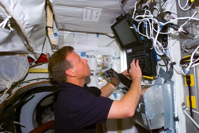 NASA image: Lindsey enters data into laptop in Spacehab