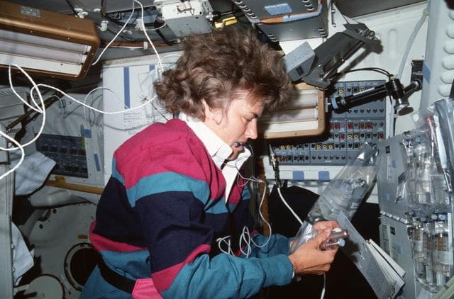 NASA image: STS-43 MS Lucid works with BIMDA-02 cell syringes on OV-104's middeck