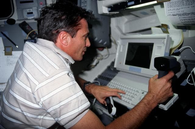NASA image: STS-43 Commander Blaha conducts DTO 1208 using laptop on OV-104's flight deck