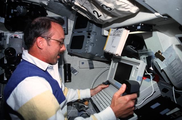 NASA image: STS-43 MS Adamson conducts DTO 1208 using laptop on OV-104's flight deck