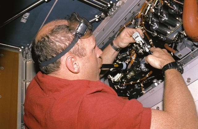 NASA image: Crewmember repairing the Regenerative Carbon Dioxide Removal System wiring.