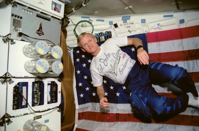 NASA image: Crewmember in the middeck beside the Commercial Generic Bioprocessing exp.