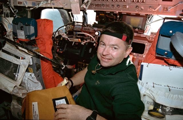 NASA image: STS-56 Commander Cameron with camera stowage bag on OV-103's flight deck