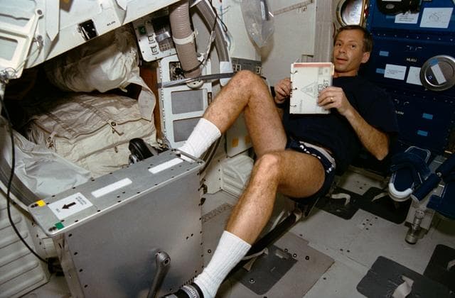 NASA image: STS-56 MS2 Cockrell pedals reclining cycle ergometer on OV-103 middeck