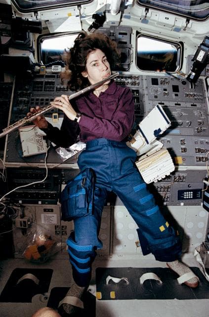 NASA image: Candid view of a crewmember playing a flute in the aft flight deck.