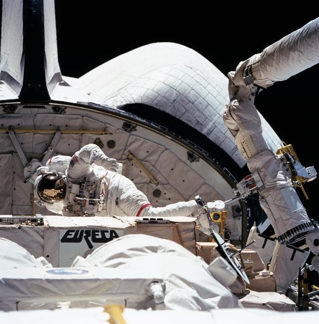 NASA image: STS-57 MS & PLC Low, in EMU and atop the RMS, is maneuvered in OV-105's PLB