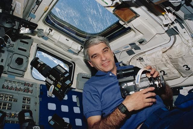 NASA image: Astronaut Sidney Gutierrez on flight deck holding Hasselblad camera