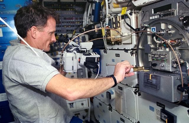 NASA image: Astronaut Joseph R. Tanner works with PCG experiment on middeck