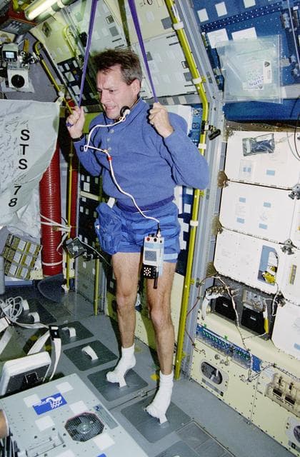 NASA image: Linnehan exercises with a bungee strap in the Spacelab module