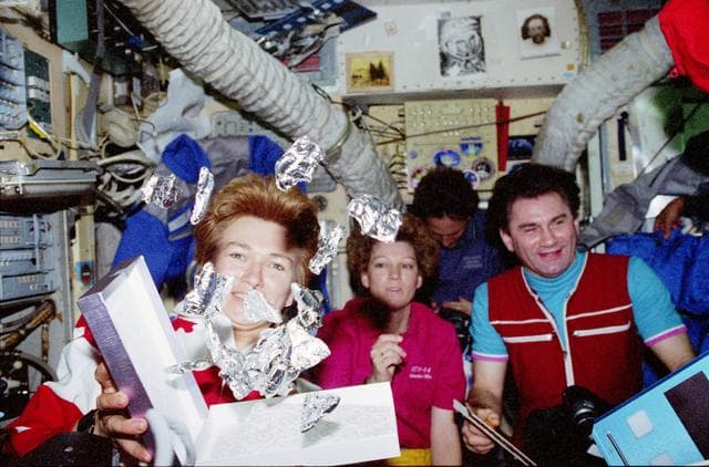 NASA image: STS-84 and Mir 23 crewmembers exchange gifts during meal after docking