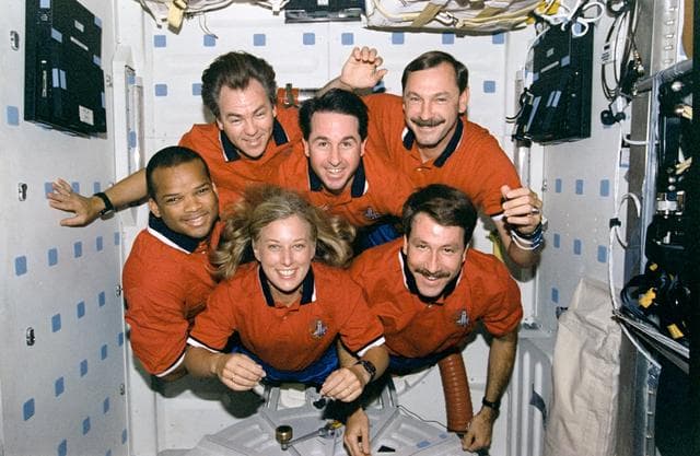 STS-85 crew portraits in the middeck hatch and in front of lockers