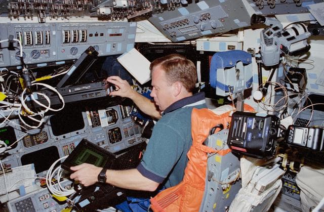NASA image: Lindsey works with several laptop computers in the flight deck