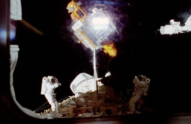 NASA image: Scott and Doi stand on the MPESS in the payload bay waiting to catch Spartan