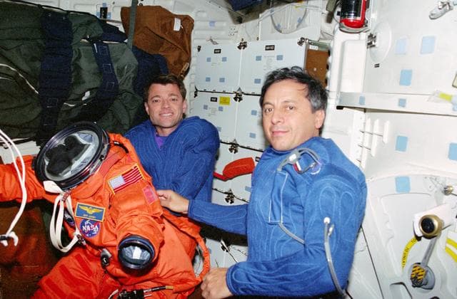 NASA image: STS-93 Tognini and Ashby prepare to put on their LES on the middeck