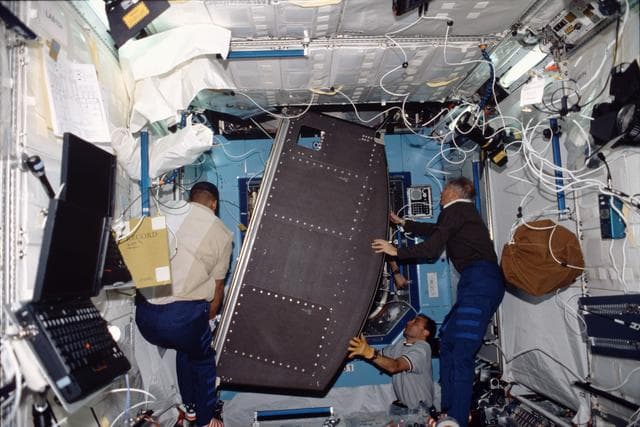 STS-98 crewmember move rack into U.S. Laboratory / Destiny module