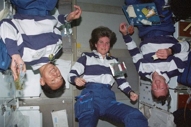 NASA image: STS-99 Mohri,Voss & Gorie pose during a meal on OV-105's middeck