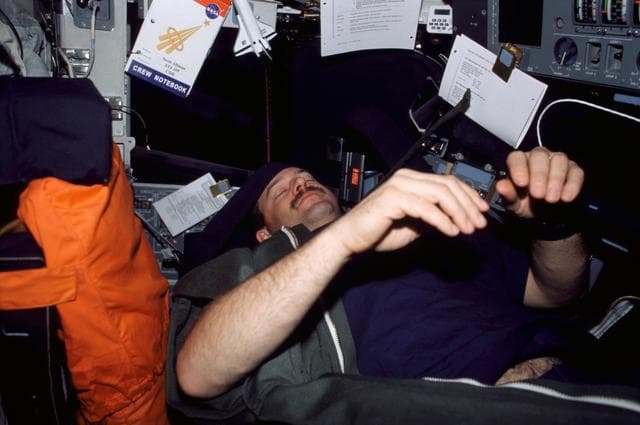 NASA image: CDR Altman in sleep restraint on flight deck